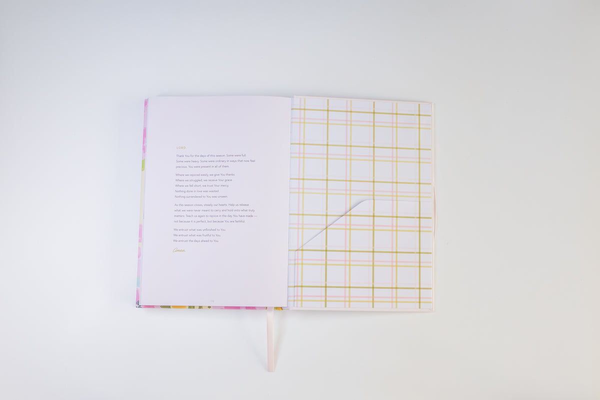 An open notebook or journal on a clean white background, showing a printed page with text on the left and a lined patterned page on the right with a ribbon bookmark hanging from the bottom.