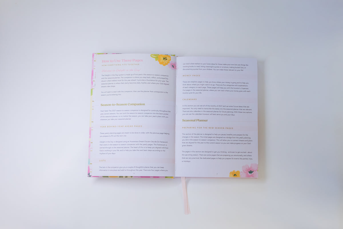 An open book or booklet laid flat on a white background, showing two printed pages with text and small pink and yellow floral illustrations near the top and bottom edges.