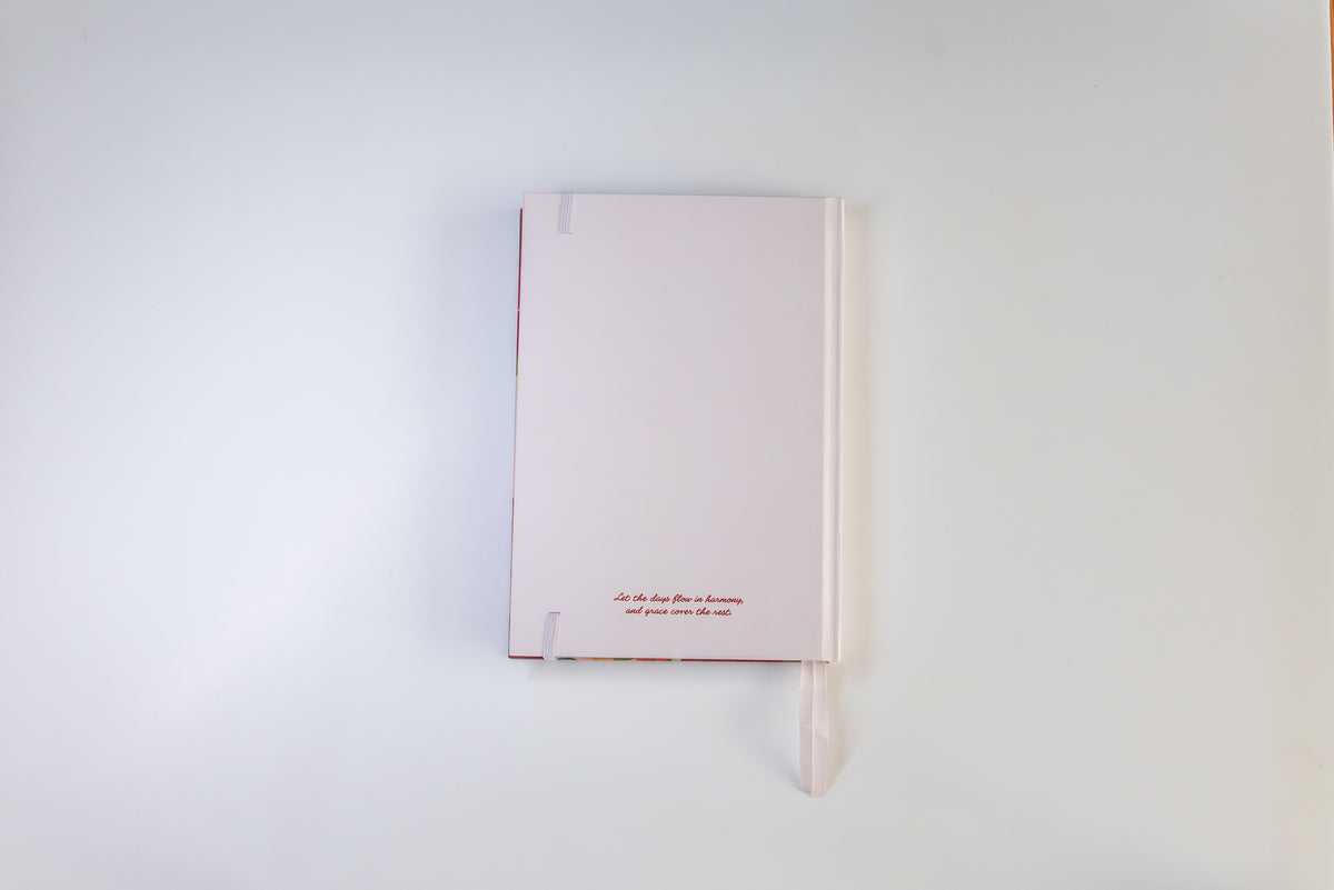 A pale pink hardcover notebook with a matching ribbon bookmark, displayed against a clean white background.