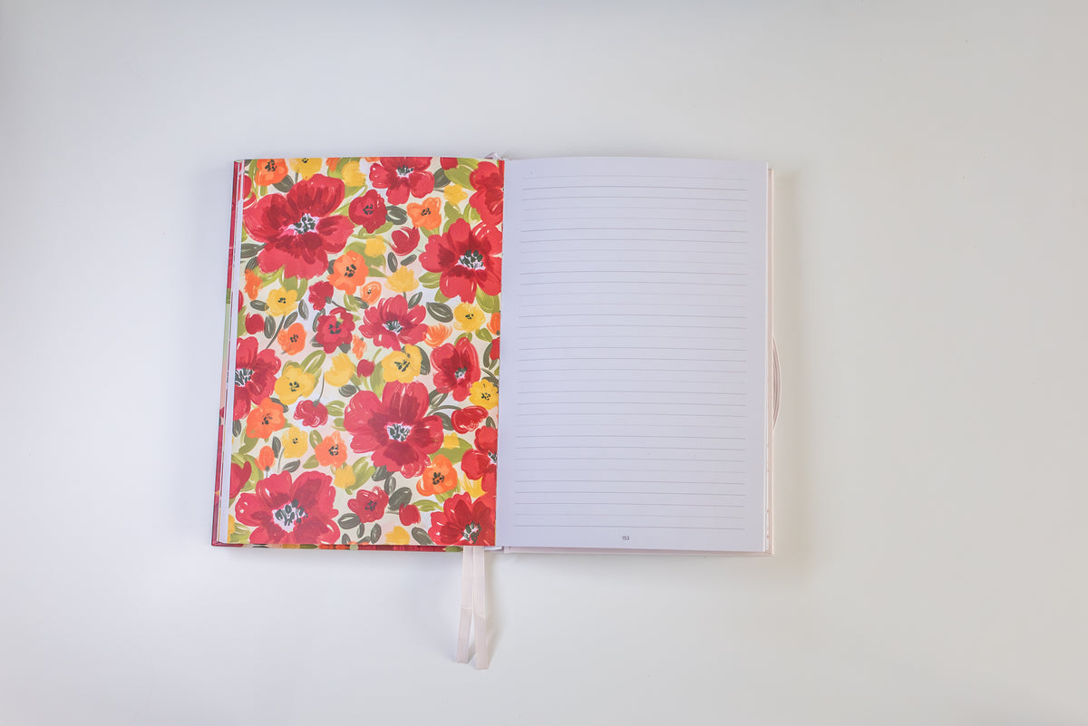 An open notebook with a vibrant floral-patterned cover on the left and lined blank pages on the right, set against a plain white background.
