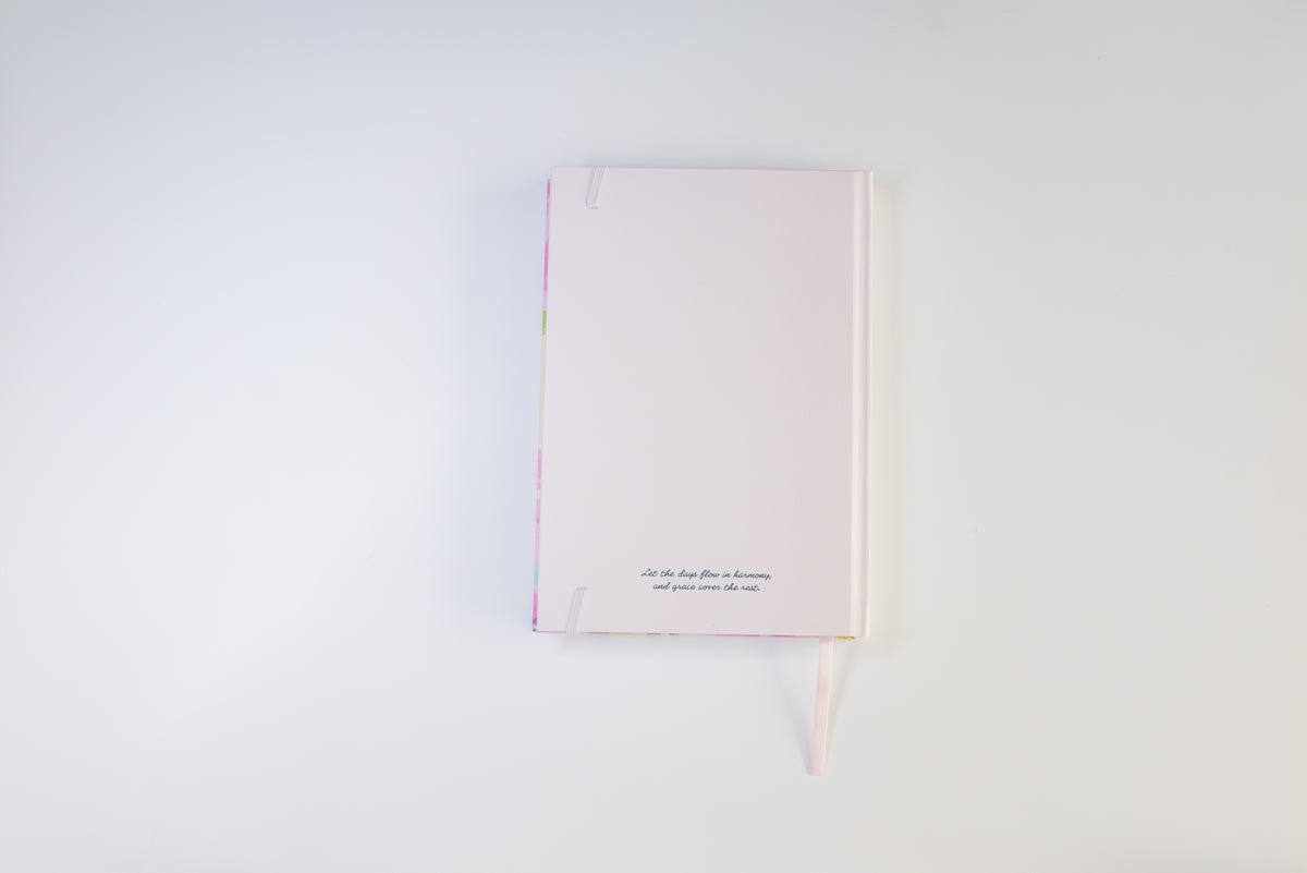 A pale pink hardcover notebook with a matching ribbon bookmark, displayed on a clean white background.