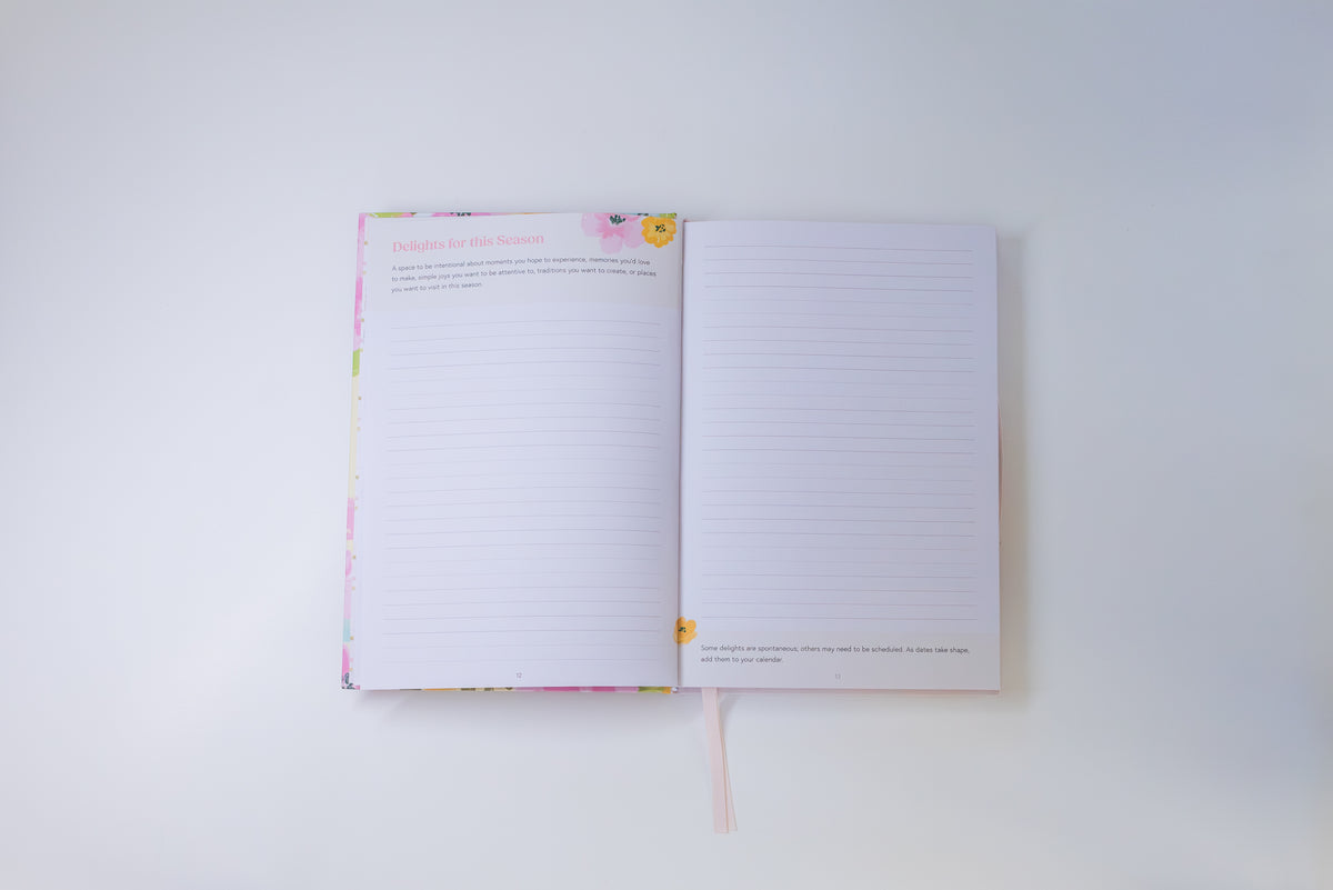 An open lined journal or notebook with a pastel floral cover, photographed from above on a plain white background.