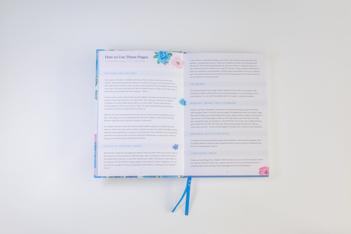 An open book with printed pages and a blue ribbon bookmark, photographed from above on a plain white background.