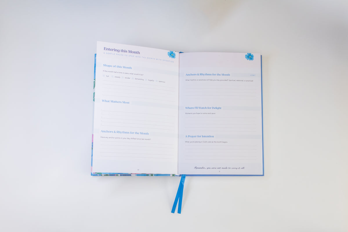 An open journal or planner with lined pages and blue ribbon bookmarks, photographed from above on a plain white background.