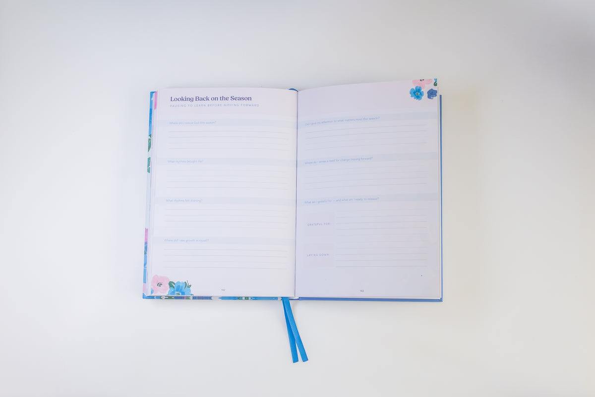 An open notebook with lined pages and blue ribbon bookmarks, photographed from above on a plain white background.
