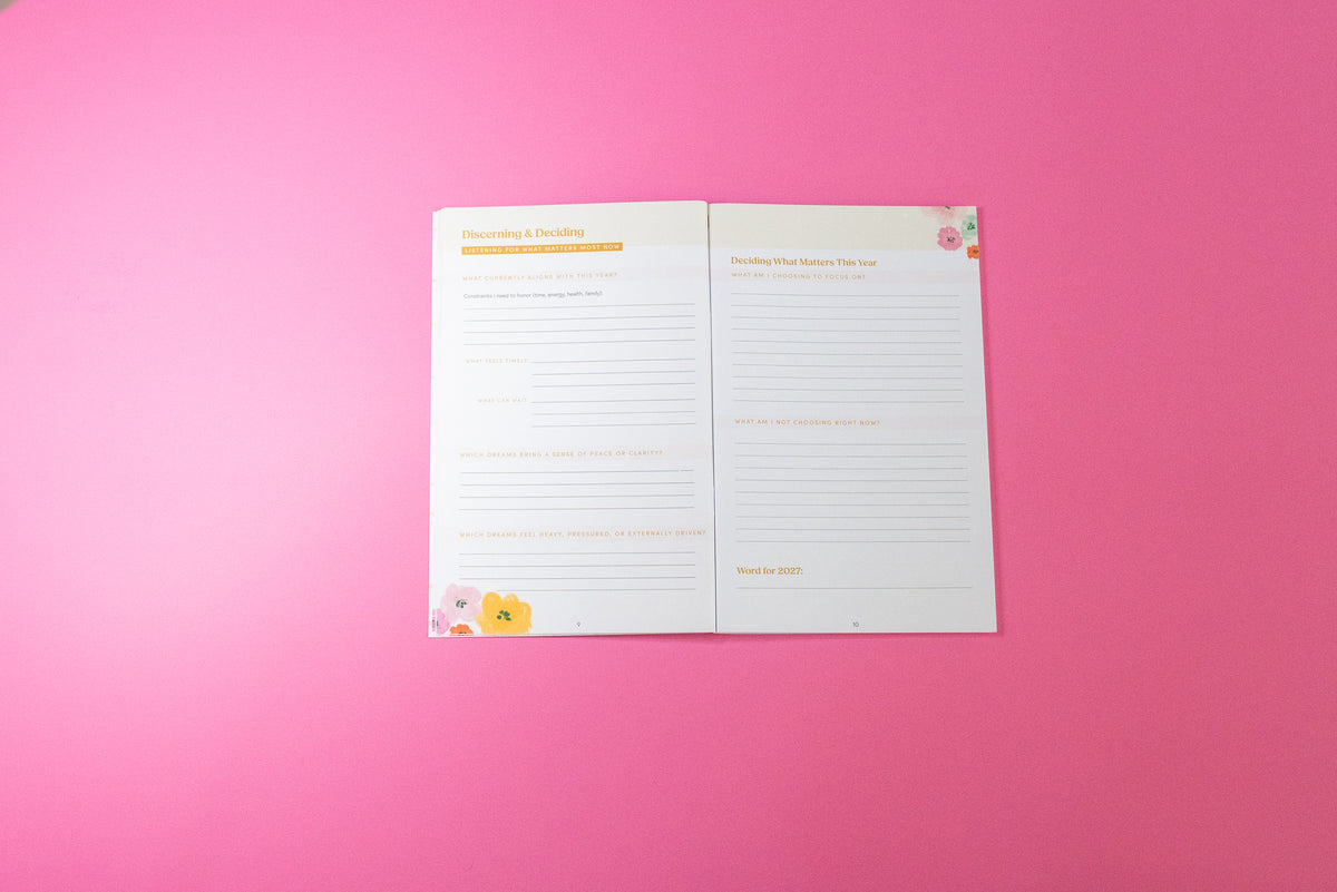 An open two-page planner insert with lined writing sections and small pastel floral illustrations, placed on a solid pink background.