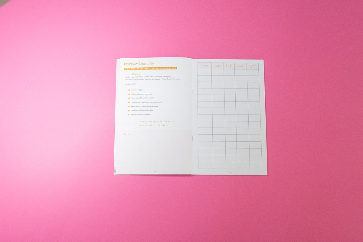 An open booklet or planner spread with printed text and a grid table on white pages, photographed on a solid pink background.