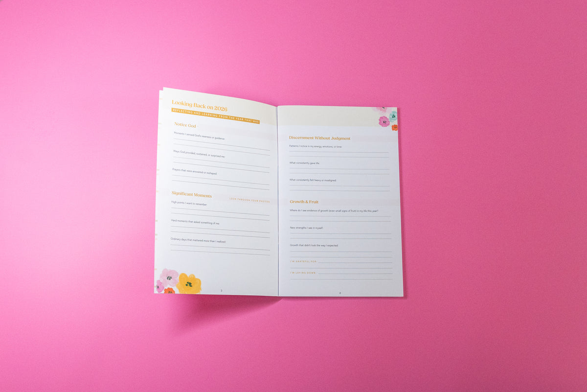 An open printable or physical journal spread on a solid bright pink background, featuring writing prompts and sections for reflection and goal setting.